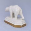 Rückansicht eines schreitenden Eisbären (Keramikfigur) auf Sockel mit Goldrand.