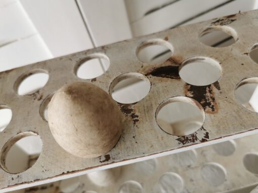 Ausschnitt eine Etage des Eierregals mit Löchern und einem Deko-Ei.