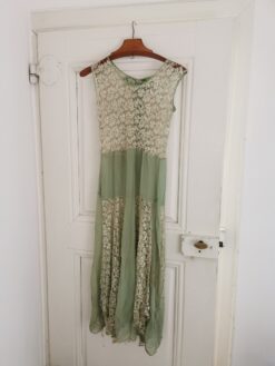 Altes Kleid in Lindgrün hängt auf einem alten Kleiderbügel an einer antiken weißen Tür.