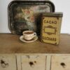 Antike Blechdose Suchard, Rückseite mit geprägtem Schild und Schriftzug Cacao. Dekoriert mit altem Tablett und einer Tasse.