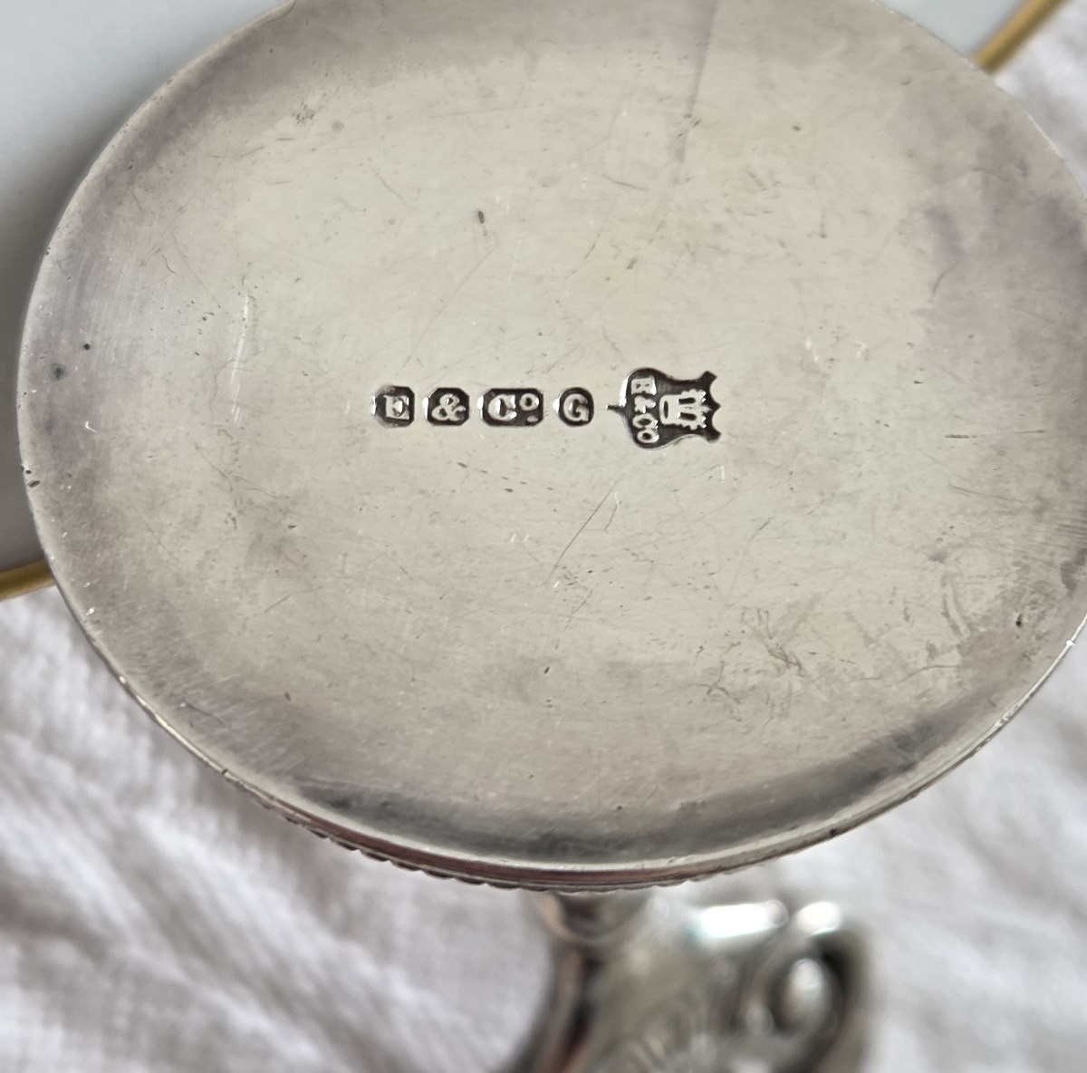Unterseite Fuß versilberter Tischkartenhalter: Buchstaben E & Co., dann G in Oval und Wappenschild mit Krone und E&Co. für Elkington & Co.