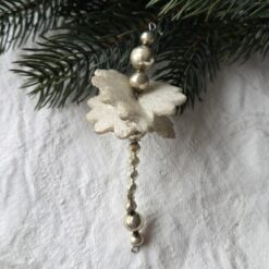 alter Christbaumschmuck, Gablonz: silberne Perlen unterschiedlicher Form und Größe bilden einen Stab. Im oberen Bereich sind zwei Blüten aus Styropor überkreuz schräg ineinander geschoben.