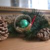 Alter Gablonzer Christbaumschmuck, spiralförmige Drahtelemente zu einer gießkanne oder Schnecke geformt, mit langer Stabperle als Ausgießer oder Scheckenhals. Zentraler Blickfang ist eine große grüne Perle.
