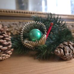 Alter Gablonzer Christbaumschmuck, spiralförmige Drahtelemente zu einer gießkanne oder Schnecke geformt, mit langer Stabperle als Ausgießer oder Scheckenhals. Zentraler Blickfang ist eine große grüne Perle.