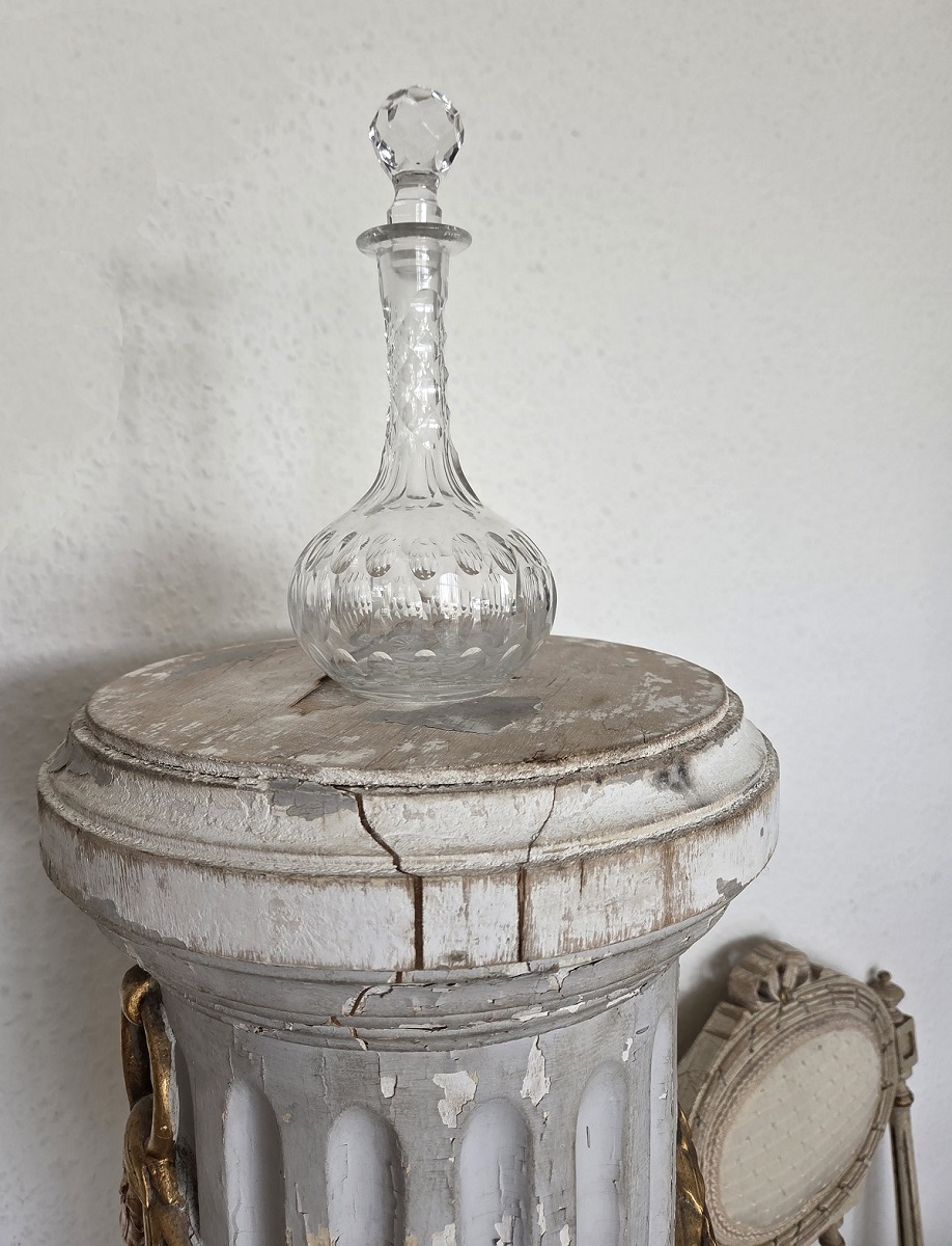 Antike Karaffe mit Olivenschliff steht auf einer Säule. Der Stöpsel der Karaffe ist ebenfalls geschliffen.