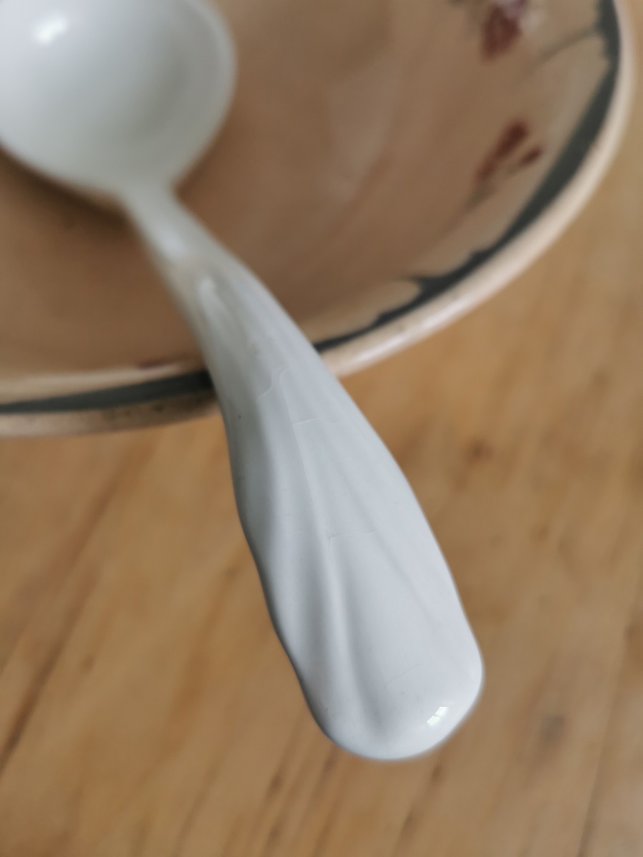 Detailaufnahme reliefierter Griff einer antiken Suppenkelle aus cremeweißer Keramik