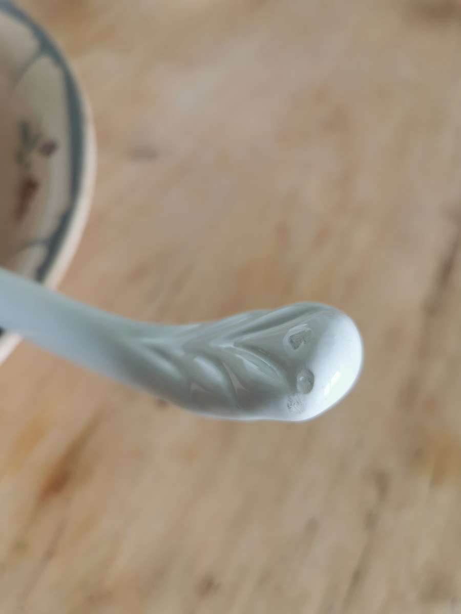 Rückseite reliefierter Griff einer antiken Suppenkelle aus cremeweißer Keramik